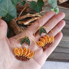 a pair of orange and brown crochet earrings on a person's hand