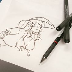 a drawing of a girl with an umbrella on paper next to markers and pencils