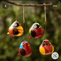 three colorful bird ornaments hanging from a tree branch