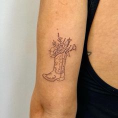 a woman's arm with a boot and flowers tattoo on the left upper arm