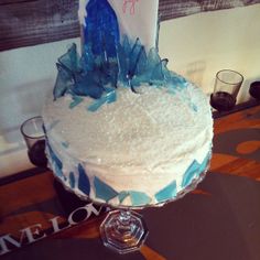 a cake with frosting and blue decorations on it sitting on a table next to two glasses