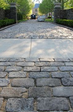 the walkway is lined with stone blocks and trimmed with trees in the backround