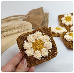 crocheted squares with flowers on them being held by a person's hand