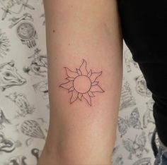 a woman's arm with a small sun tattoo on the left side of her arm