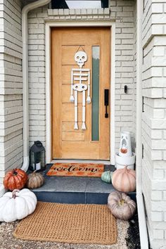 a front door decorated with pumpkins and skeleton decorations