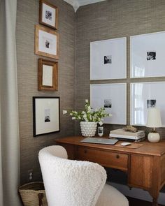 a desk with some pictures on the wall and a chair in front of it next to a window