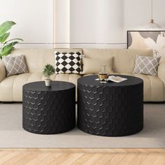 two black tables sitting on top of a wooden floor in front of a white couch