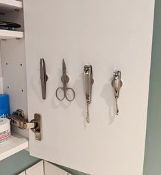 there are three pairs of scissors hanging on the wall in this kitchen with white cabinets