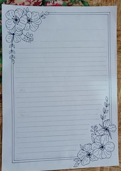 a piece of lined paper with flowers and vines on it, sitting on a table