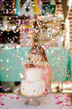 a birthday cake sitting on top of a table with confetti all around it