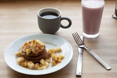 a breakfast plate with pancakes and fruit next to a cup of coffee on a table