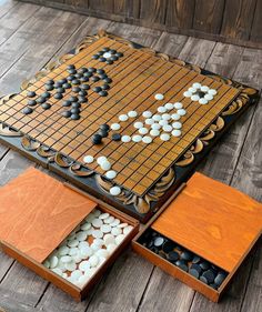 a wooden board game set up on top of a wooden floor with white and black stones