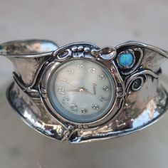 From Porans Watches collection: Unique Silver Bohemian Flexible Cuff Watch with gemstone: TURQUOISE/GARNET/ PEARL/OPAL inlaid. Dimensions: Front Width: 36 mm\ 1.44 inches. Back width: 14 mm\ 0.56 inches.  Size: Can fit any wrist Our watch is top quality stainless still, analog, Japanese movement with water resistance (up to 3 atmospheres) and it is powered by a battery that lasts about 3 years. The battery can be exchanged. Please notice that because the watch is made to order the watch mechanis Cuff Bracelet Strap Watches, Timeless Metal Cuff Bracelet As Gift, Adjustable Silver Analog Jewelry And Watches, Silver Analog Jewelry And Watches As Gift, Timeless Analog Jewelry For Anniversary, Adjustable Silver Jewelry And Watches With Round Dial, Adjustable Analog Jewelry For Formal Occasions, Timeless Round Cuff Bracelet As Gift, Watches Collection