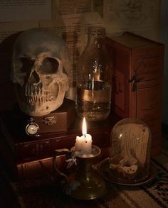 a candle is lit in front of a skull and other items on a table with books