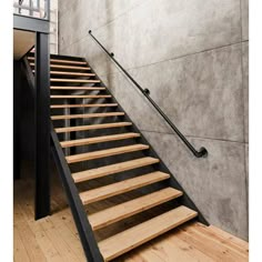 a set of stairs leading up to the second floor in a modern building with concrete walls and wooden floors