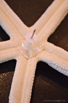 a white starfish with a candle in it's center on a black surface