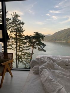 a bed sitting next to a window with a view of the water and mountains in the distance