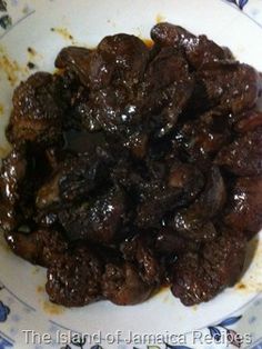 a white plate topped with meat covered in gravy on top of a blue and white table cloth