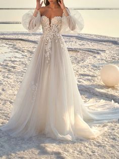 a woman standing on top of a beach next to the ocean wearing a white dress