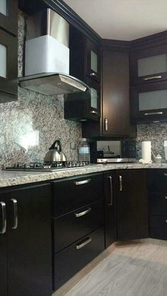 a kitchen with black cabinets and marble counter tops