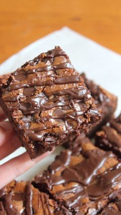 someone holding up some chocolate brownies on a plate