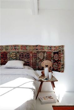 a bedroom with a bed, table and rug on the wall above it's headboard