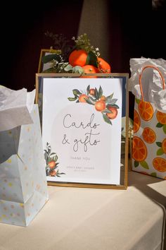 there is a card and gift box on the table with oranges in it's packaging