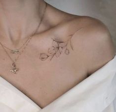 a woman wearing a white dress has a flower tattoo on her chest and is looking at the camera