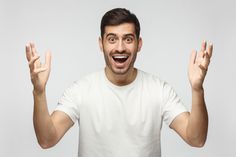 a man with his hands in the air and making an odd face while standing against a white background