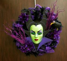 a wreath with a green mask and purple flowers