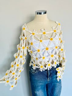 a white top with yellow daisies on the shoulders and sleeves, sitting on a mannequin's head