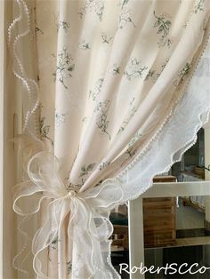 the curtains are hanging on the wall in front of the mirror, and there is a bow tied to the curtain