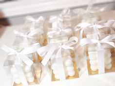 small clear boxes filled with white candies tied in ribbon and bowknots