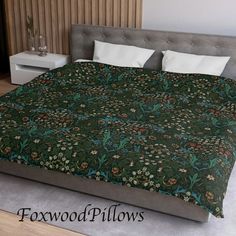 a bed with a green floral comforter on top of it next to pillows and a night stand