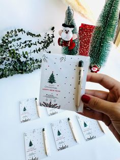 a hand holding a pen next to some christmas cards