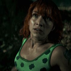 a woman with red hair wearing a green shirt and black polka dots on her tank top