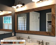 a bathroom with two sinks, mirrors and lights on the wall above them is shown