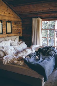 an unmade bed with white sheets and pillows in a rustic cabin style bedroom area