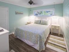 a bed sitting in a bedroom next to a white dresser and window on top of a hard wood floor