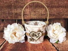 two white flowers are sitting next to an old bucket with a heart on the handle