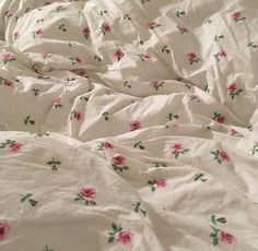 an unmade bed with pink roses on it