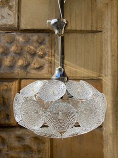 a glass chandelier hanging from the ceiling in front of a stone wall and door