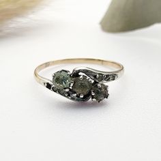 three stone ring sitting on top of a white surface