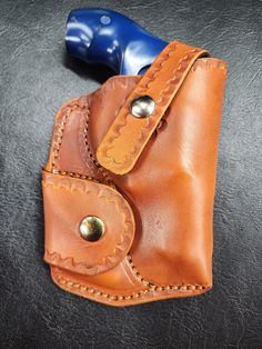 a brown leather pouch with a blue plastic object in the corner on a black surface