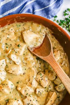 a wooden spoon in a pot full of chicken and dumplings with gravy