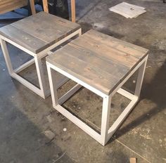 two wooden tables sitting next to each other on top of a cement floor in a warehouse