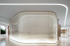 a curved glass wall in the middle of a room with white walls and flooring