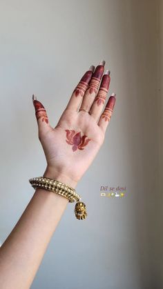 a woman's hand with hendi and bracelets on her left arm, showing the palm