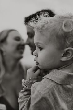 a black and white photo of a woman holding a baby in front of her face