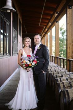 a bride and groom standing in front of some wine barrels at their wedding reception venue